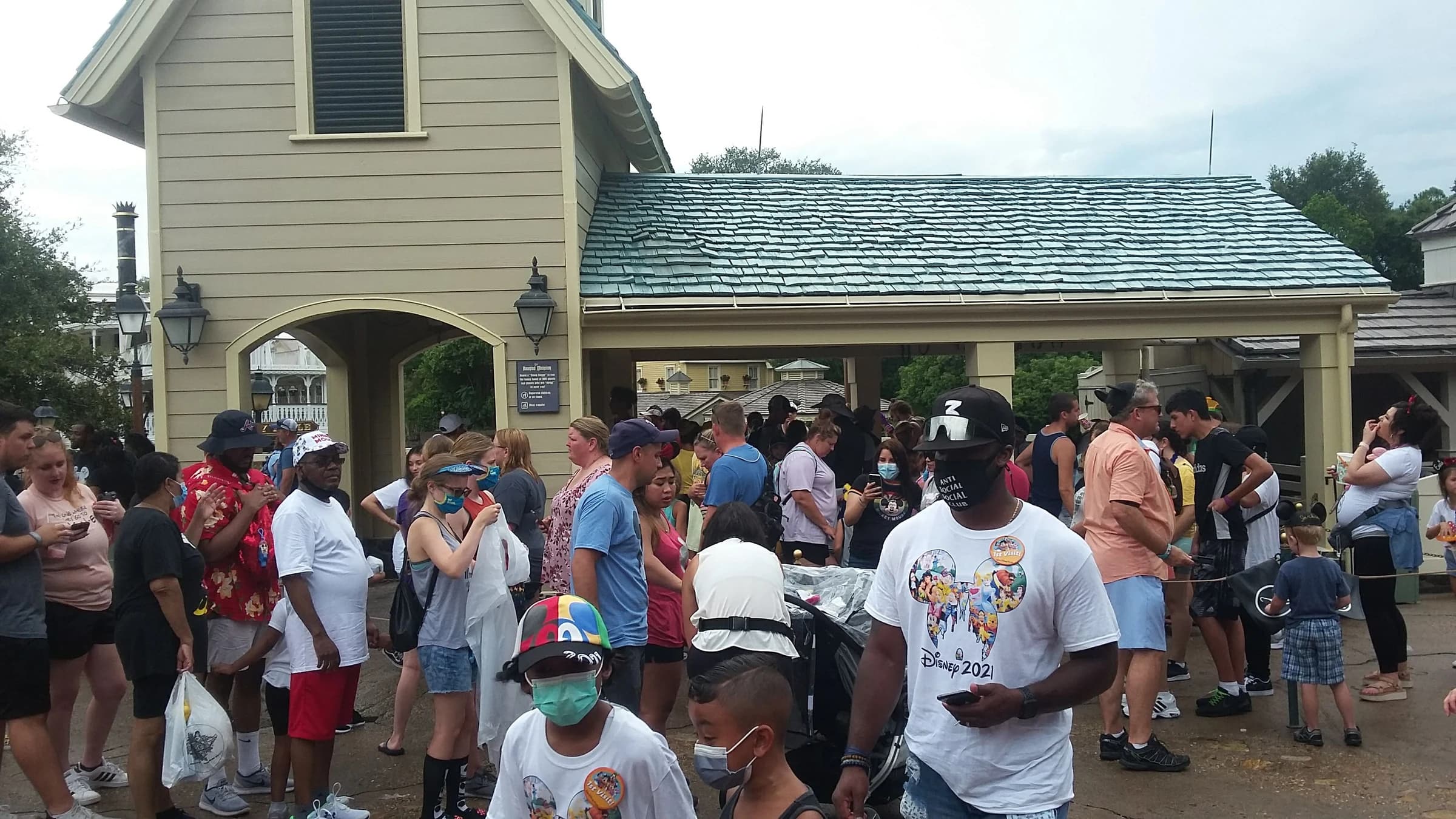 A dense crowd of visitors waiting in the queue area outside the Haunted Mansion at Magic Kingdom.